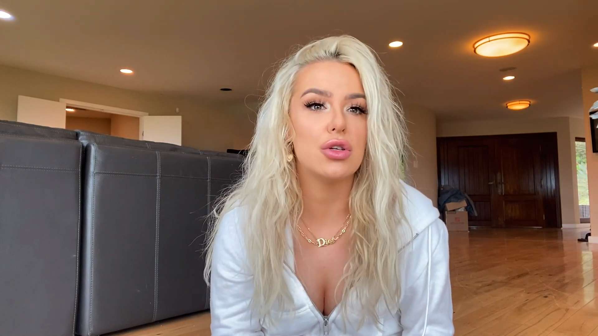 Tana Mongeau in white hoodie sitting on floor