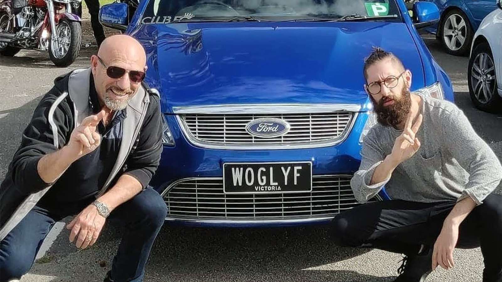 Mark Bonanno poses with his father in front of a blue Ford sedan.