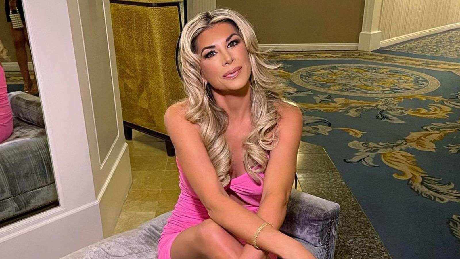 Alexis Bellino sitting on a pouffe in a pink dress