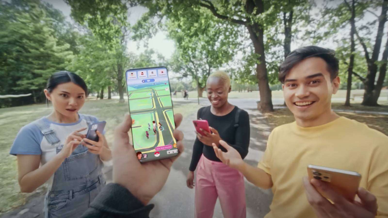A group of people are playing Pokemon go on a path, with one holding a phone aloft with the game visible