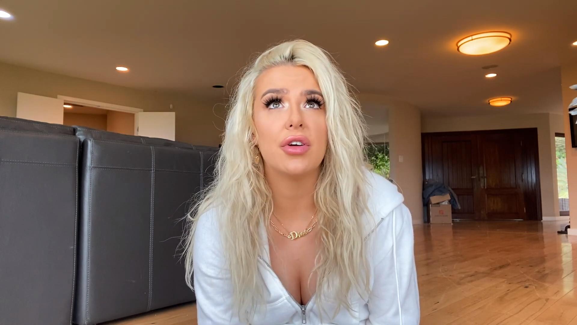 Tana Mongeau in white hoodie sitting on floor