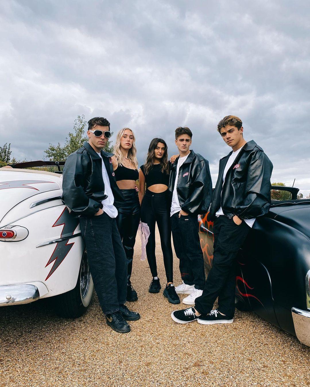 Wave house members posing with two cars