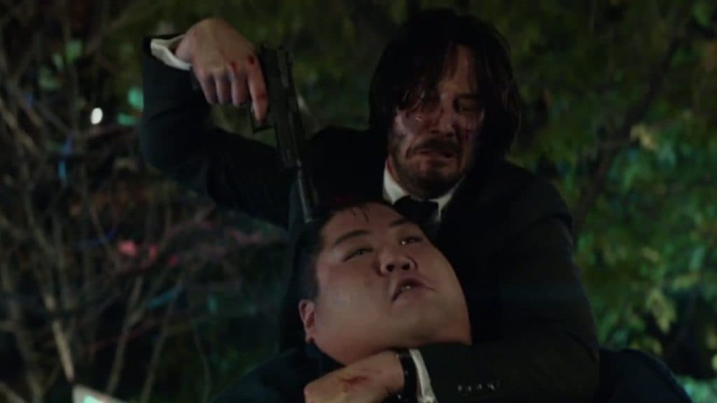Keanu Reeves as John Wick shooting an opponent in the head