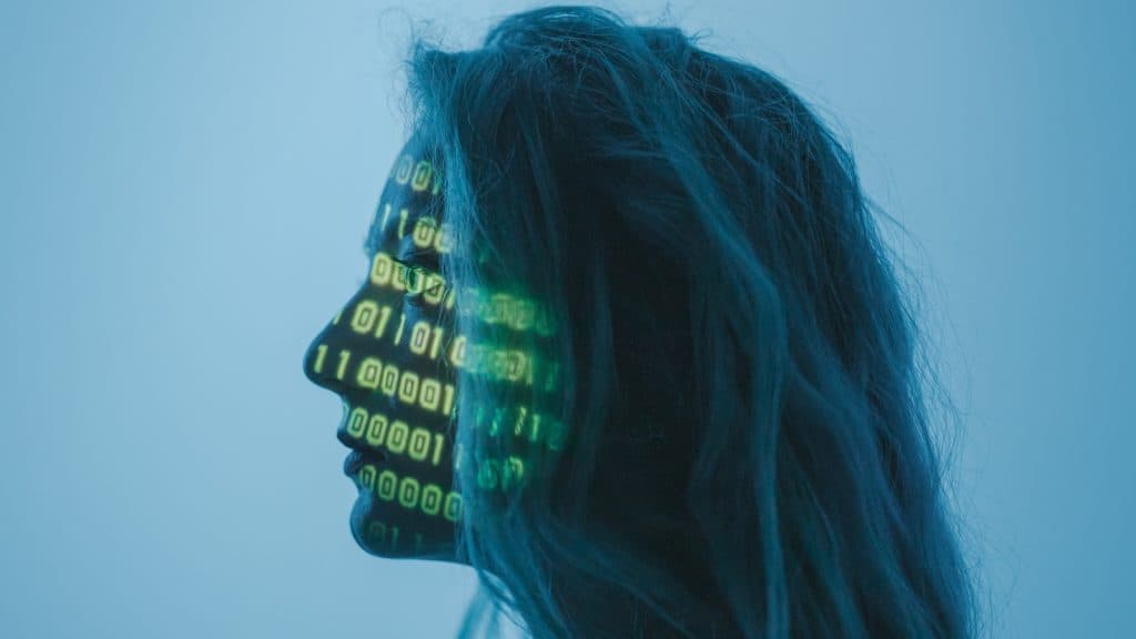 A woman with code projected on face on a blue background
