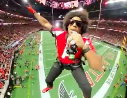 Ludacris in a harness flying over an NFL football field