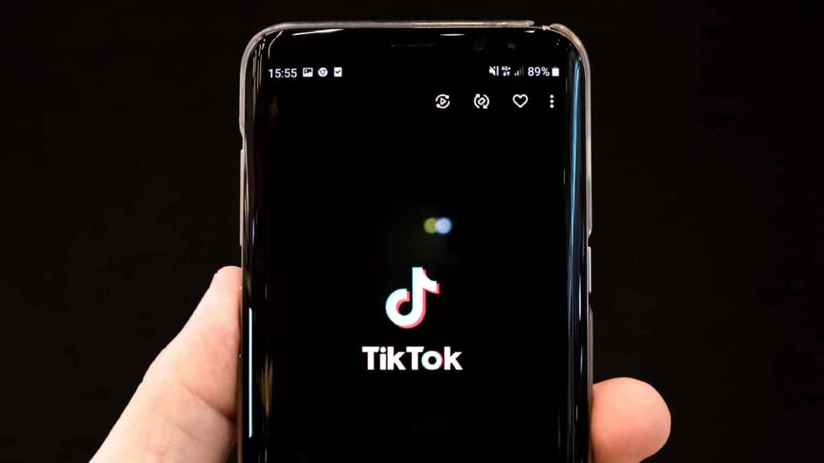 Hand holding a phone with the TikTok logo on it