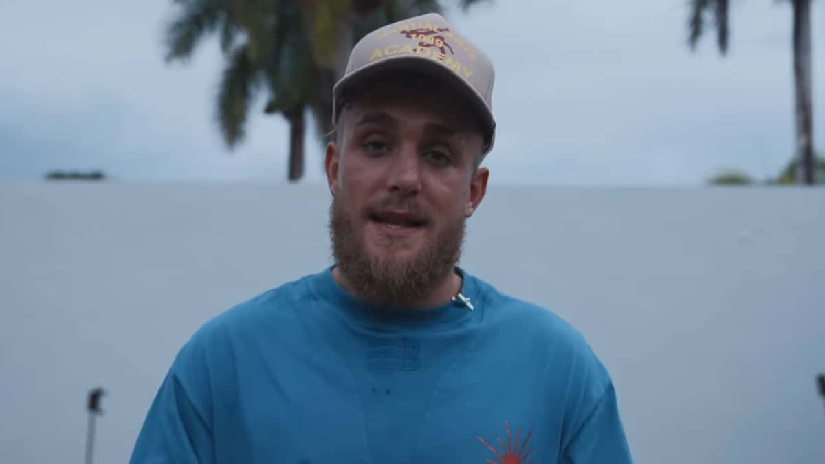 Jake Paul talking to camera in blue shirt and white hat outside