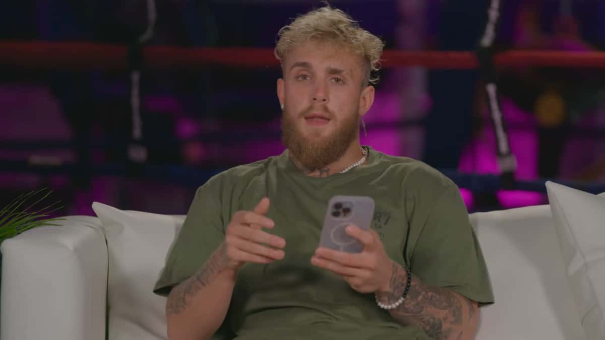 Jake Paul sat on couch talking to camera while holding phone