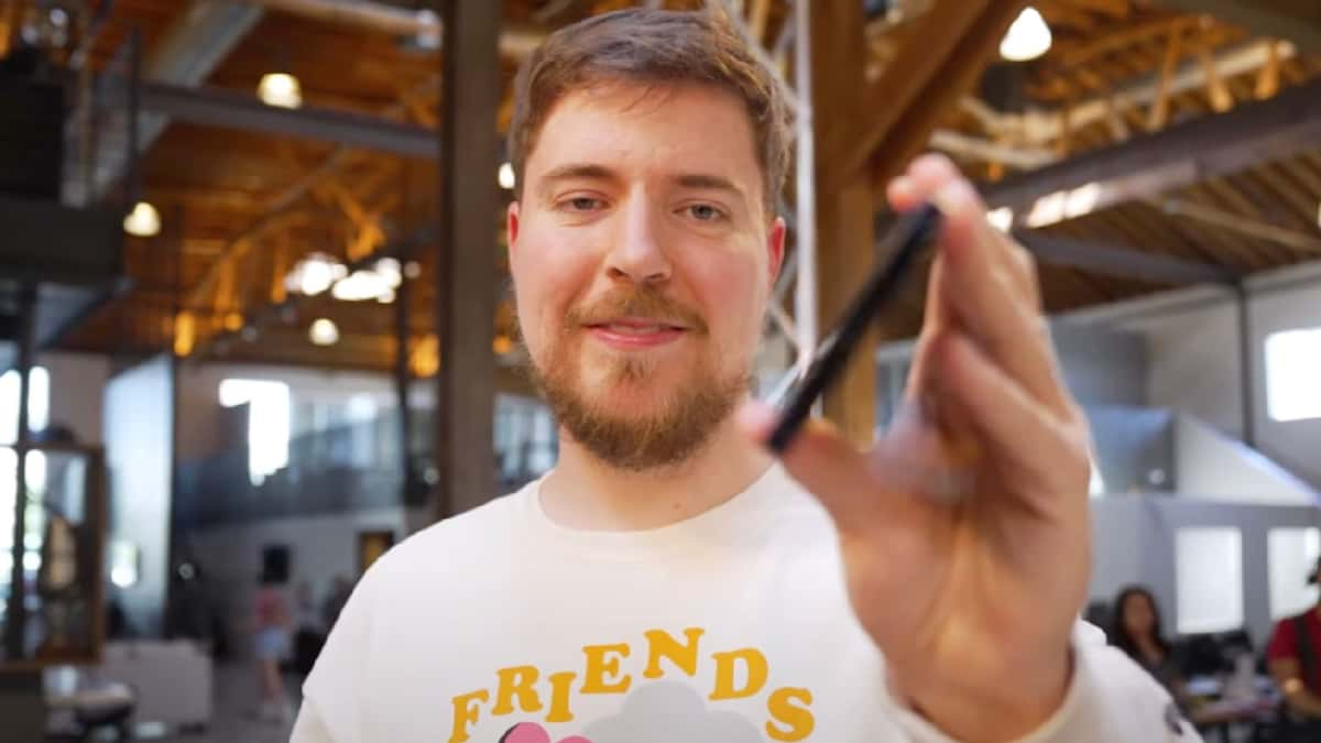 mrbeast holding phone to camera in white and yellow shirt