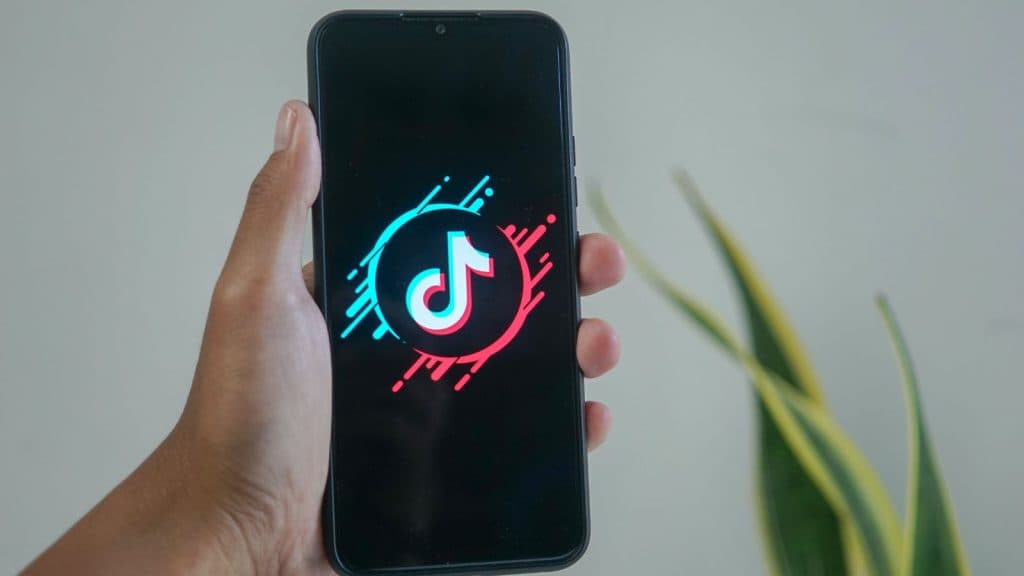 Hand holding a phone with TikTok logo