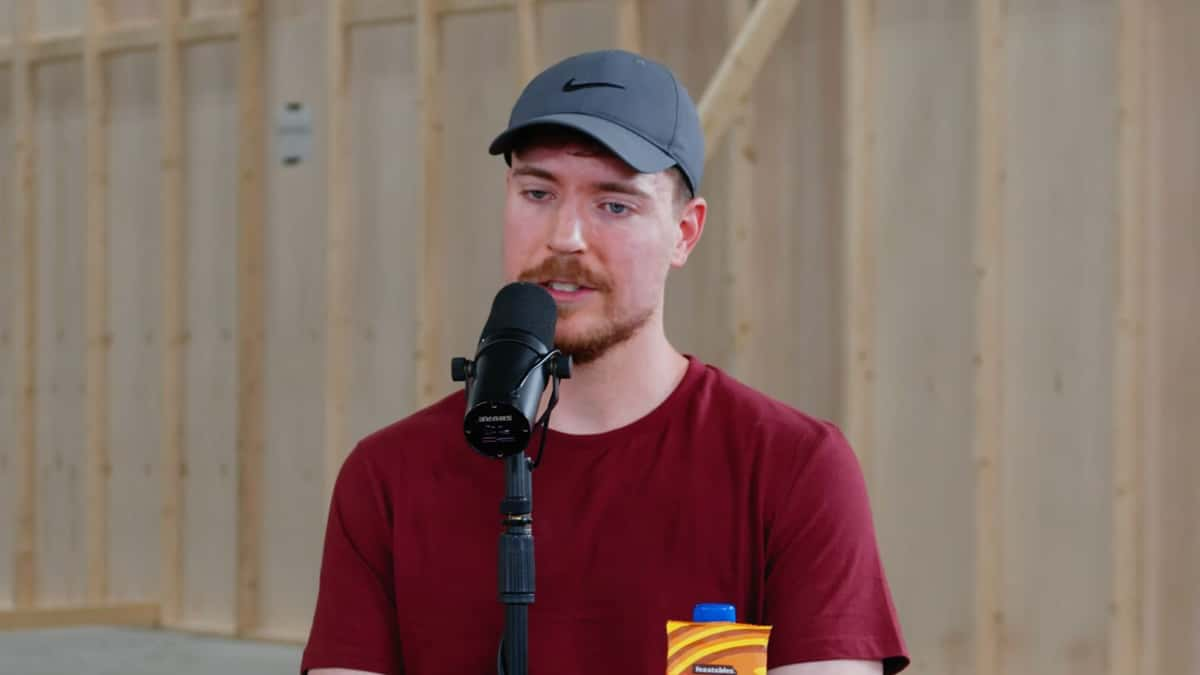 MrBeast talking into mic wearing red shirt and grey hat