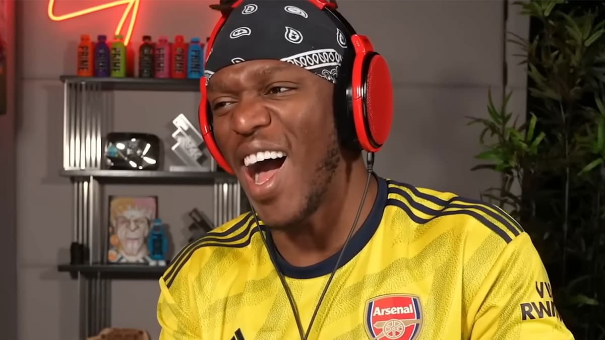 KSI laughing while wearing yellow Arsenal FC shirt