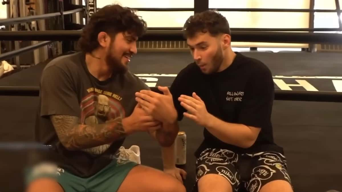 Adin Ross and Dillon Danis sat ringside on boxin gring looking at phone