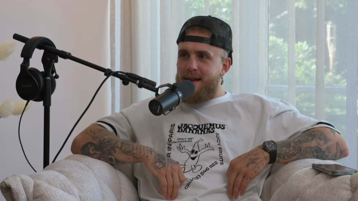 Jake Paul in white shirt talking into microphone while sat on couch