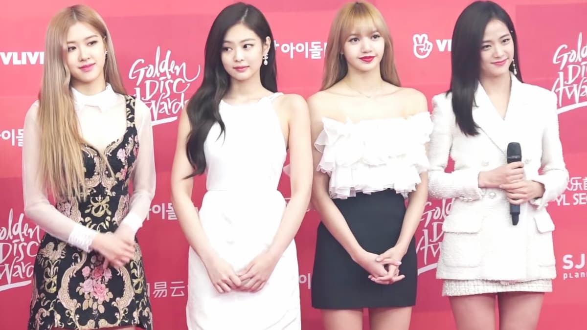 Blackpink standing in elegant attire on a red carpet