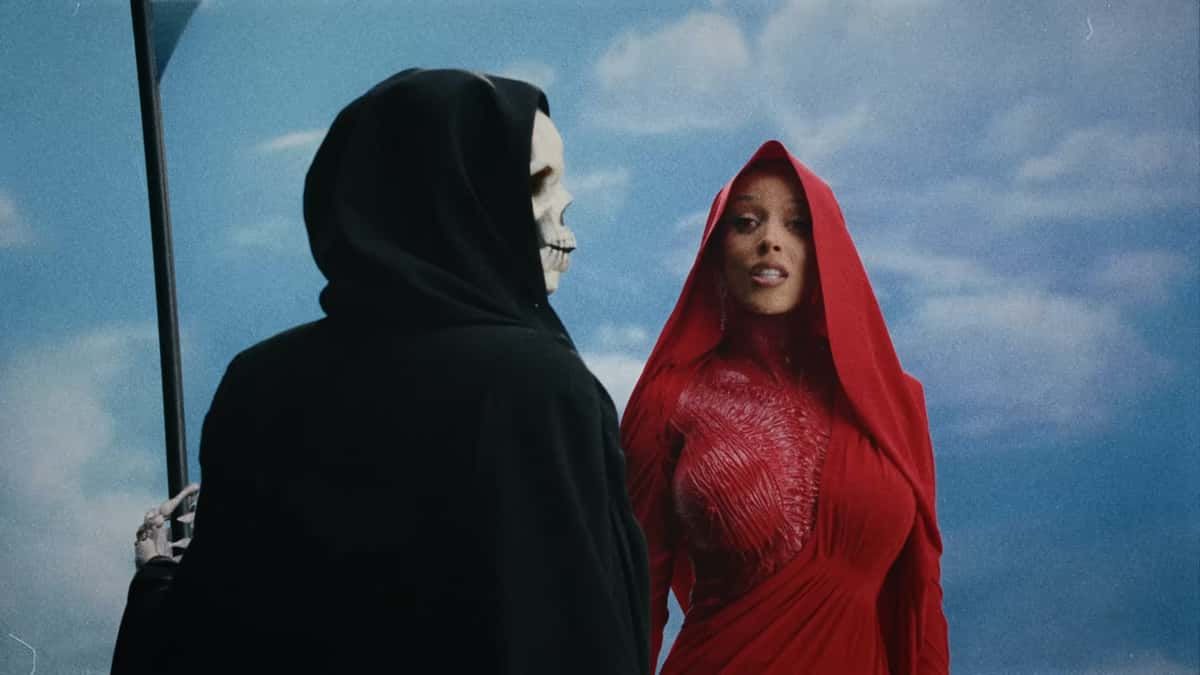 Doja Cat in a blood read outfit standing next to the Grim Reaper