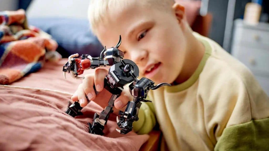 A kid playing with the LEGO Marvel Venom Mech Armor vs. Miles Morales set.