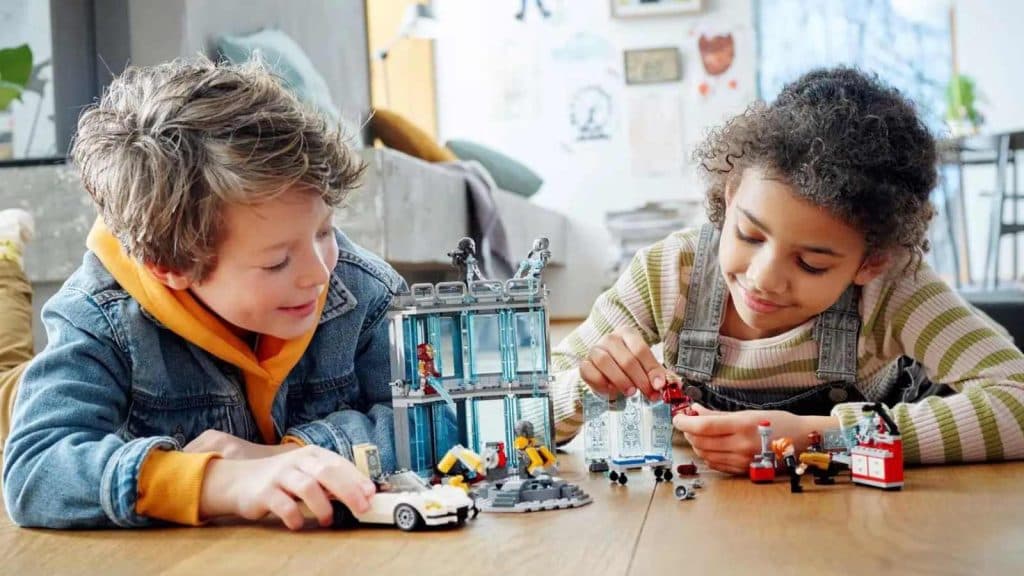 Two children playing with the LEGO Marvel Iron Man Armory set.