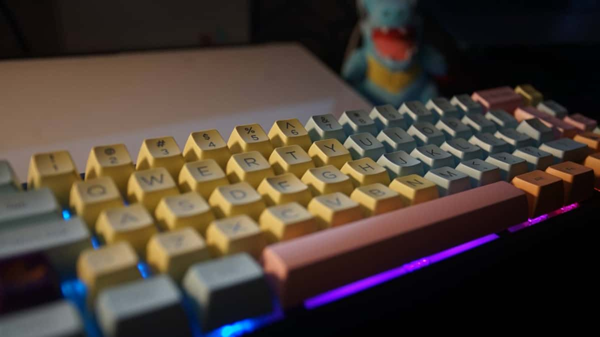 A side view shows a mechanical keyboard on a black desk mat