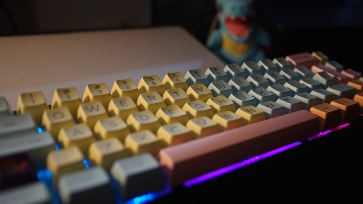 A side view shows a mechanical keyboard on a black desk mat