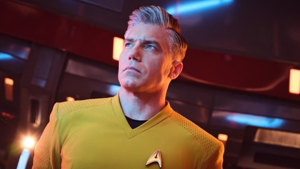 Captain Christopher Pike from Star trek: Strange New Worlds stands on the bridge of the USS Enterprise during a red laert.