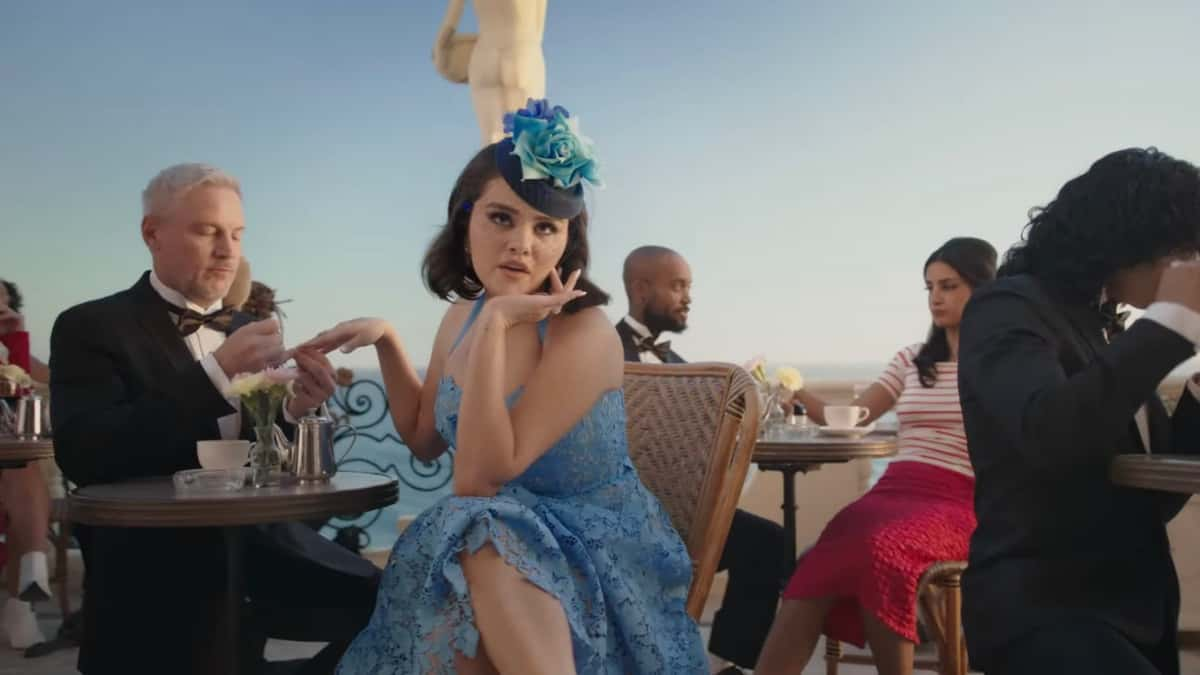 Selena Gomez having her nails done while sitting in a blue dress outside