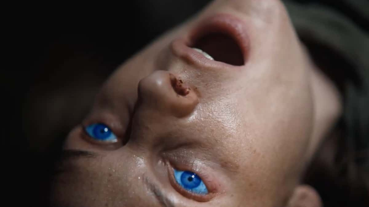 Rebecca Ferguson as Lady Jessica in Dune 2. Lady Jessica lies on the floor, mouth agape in pain, as her eyes glow blue after ingesting the Water of Life.