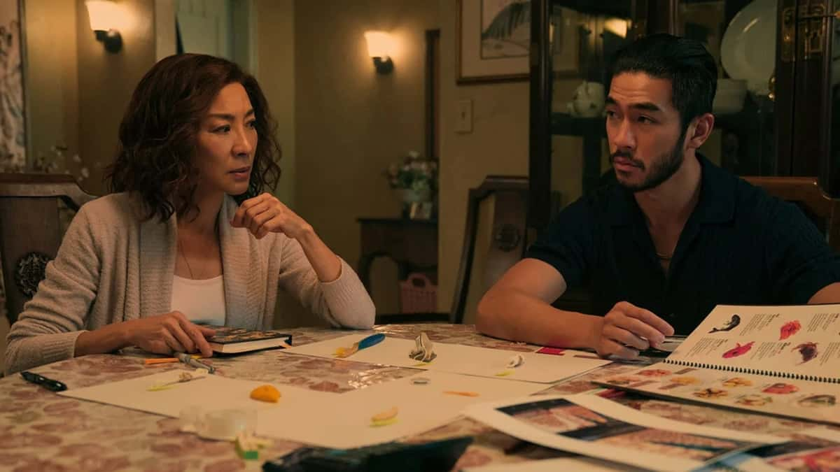 Michelle Yeoh as Eileen "Mama" Sun and Justin Chien as Charles Sun sitting at the table with papers in front of them