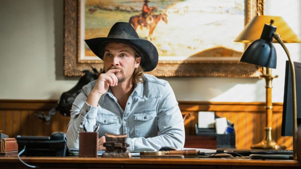 Luke Grimes as Kayce Dutton on Yellowstone, sitting at a desk