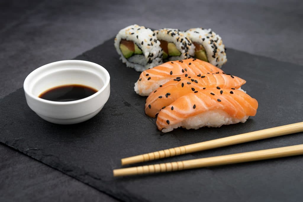 A plate of sushi and nigiri with chopsticks.