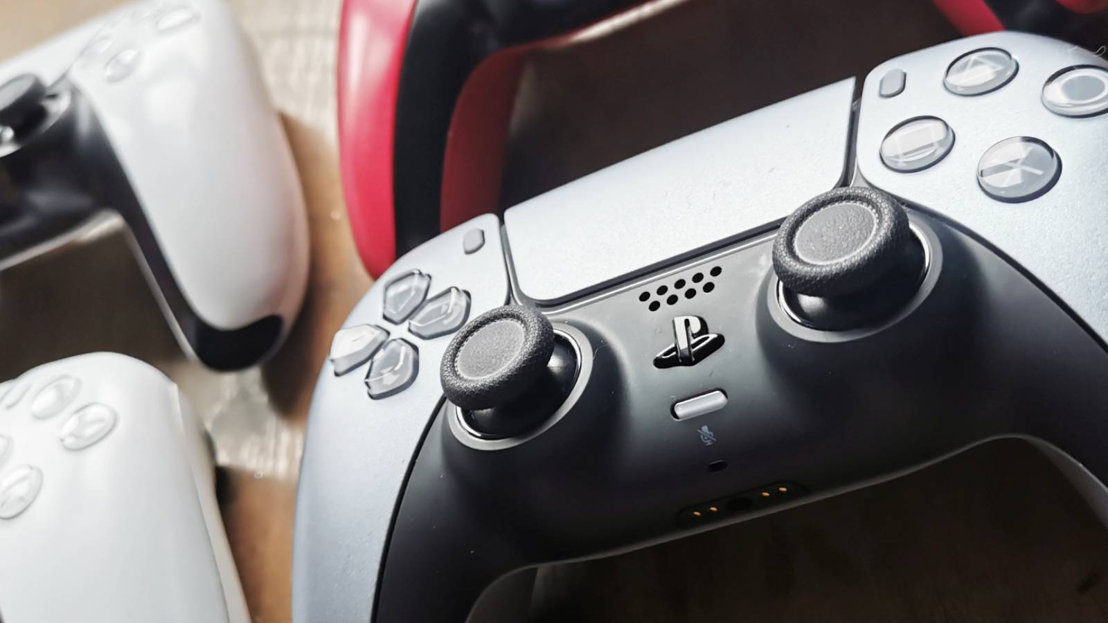 Image of four PS5 DualSense controllers on a wooden coffee table.