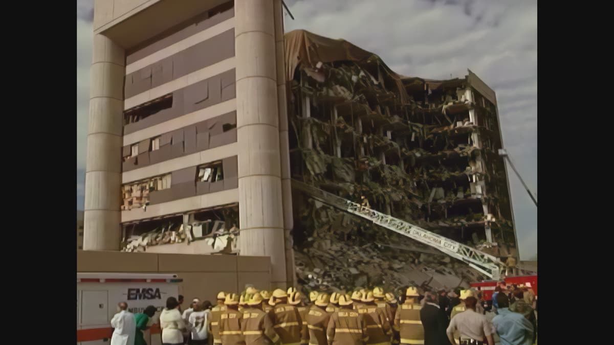 Firefighters stand below a decimated government building.