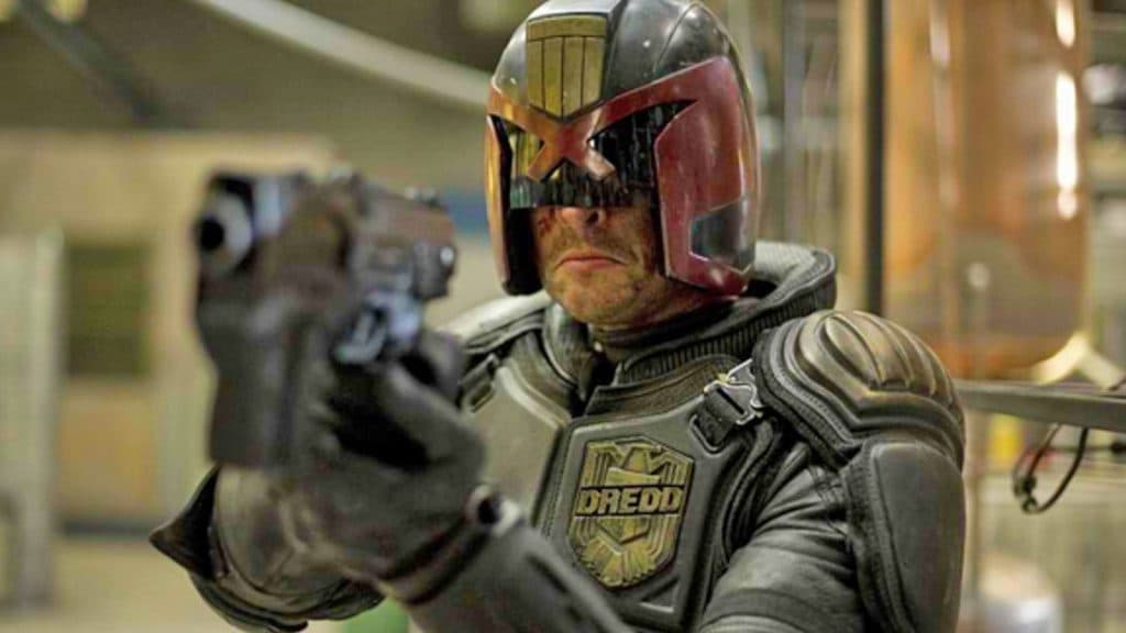 Judge Dredd grimaces as he points his gun.