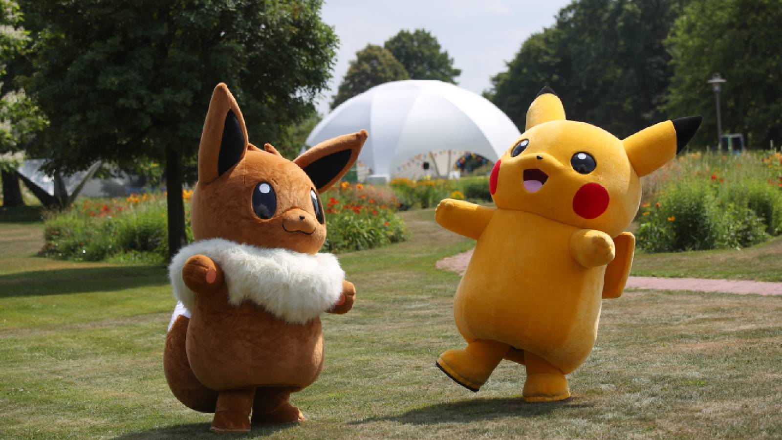 People in Pikachu and Eevee costumes play in a field