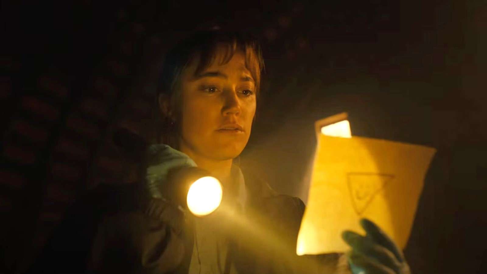 Maika Monroe (who stars alongside Nicolas Cage) as Lee Harker looking at a piece of paper in Longlegs