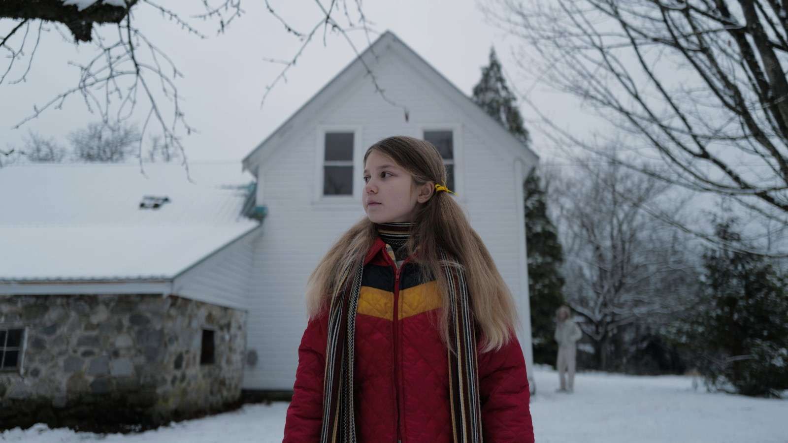 A still from the Longlegs trailer showing a girl standing outside a snow-covered house