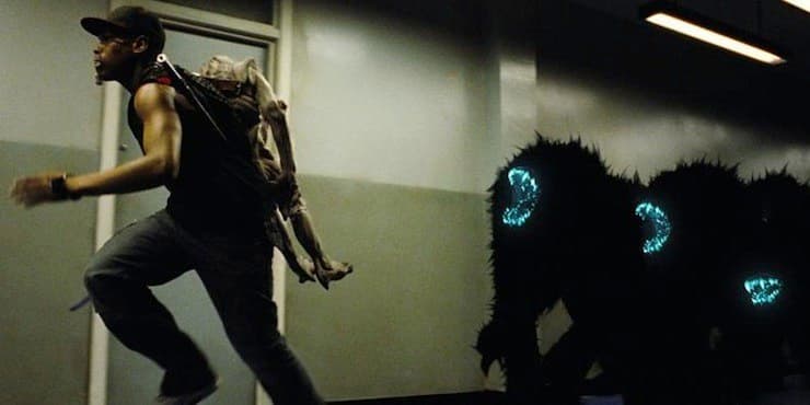 A boy runs away from a group of black aliens with glowing blue teeth in a corridor