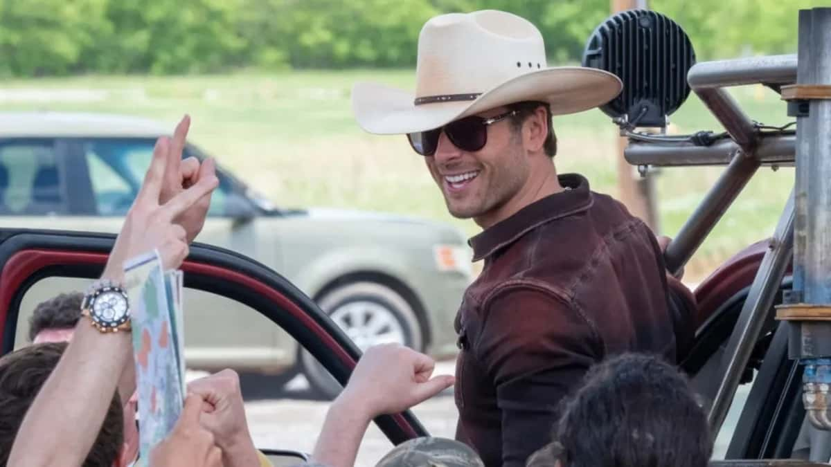 Glen Powell as Tyler Owens in Twisters, stepping out of a truck and smiling