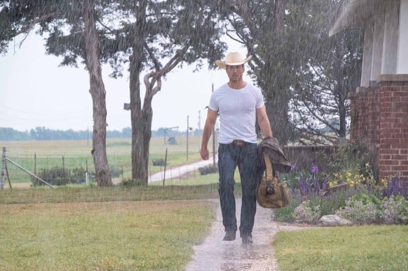 Glen Powell as Tyler Owens in Twisters, in the rain wearing a cowboy hat