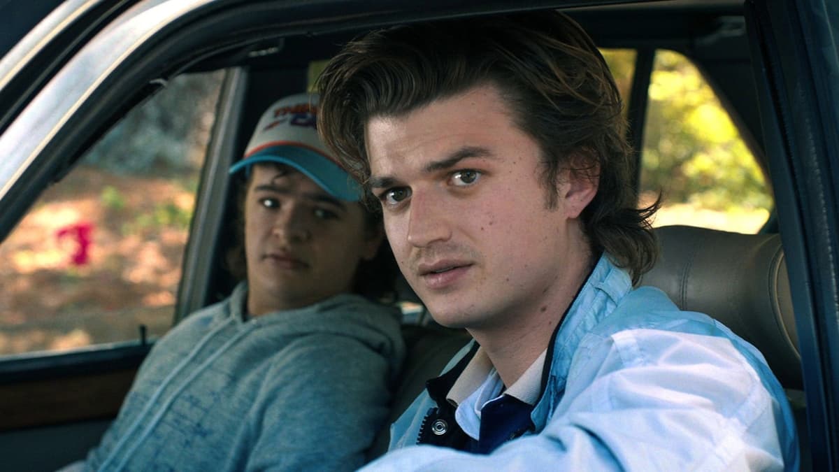 Joe Keery as Steve in Stranger Things, sitting in a car