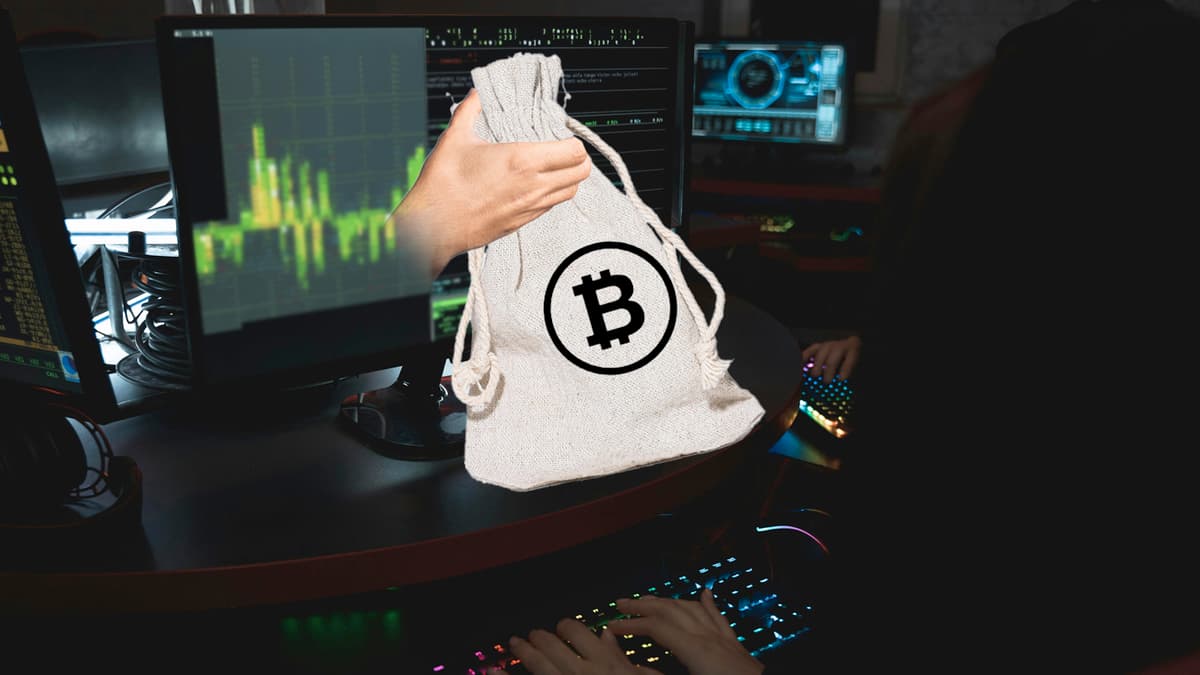 Ransomware represented by a bag of cash with the bitcoin logo on it being handed through a monitor