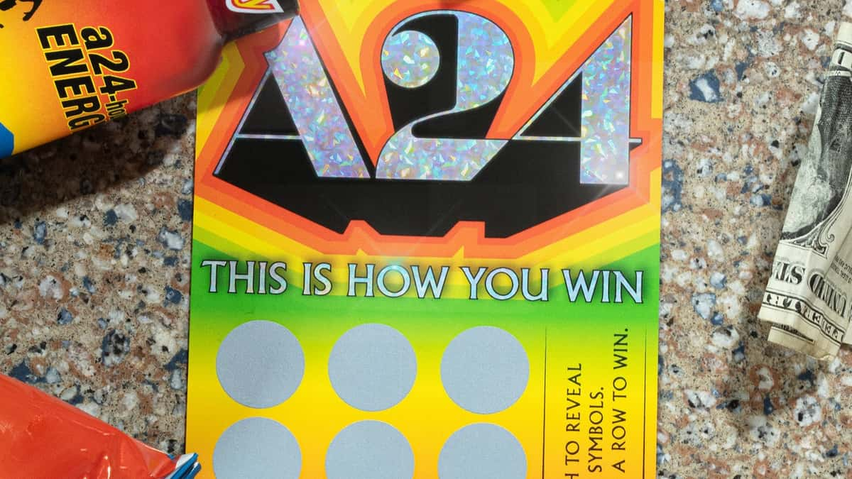 The A24 scratch card, pictures next to a dollar bill.