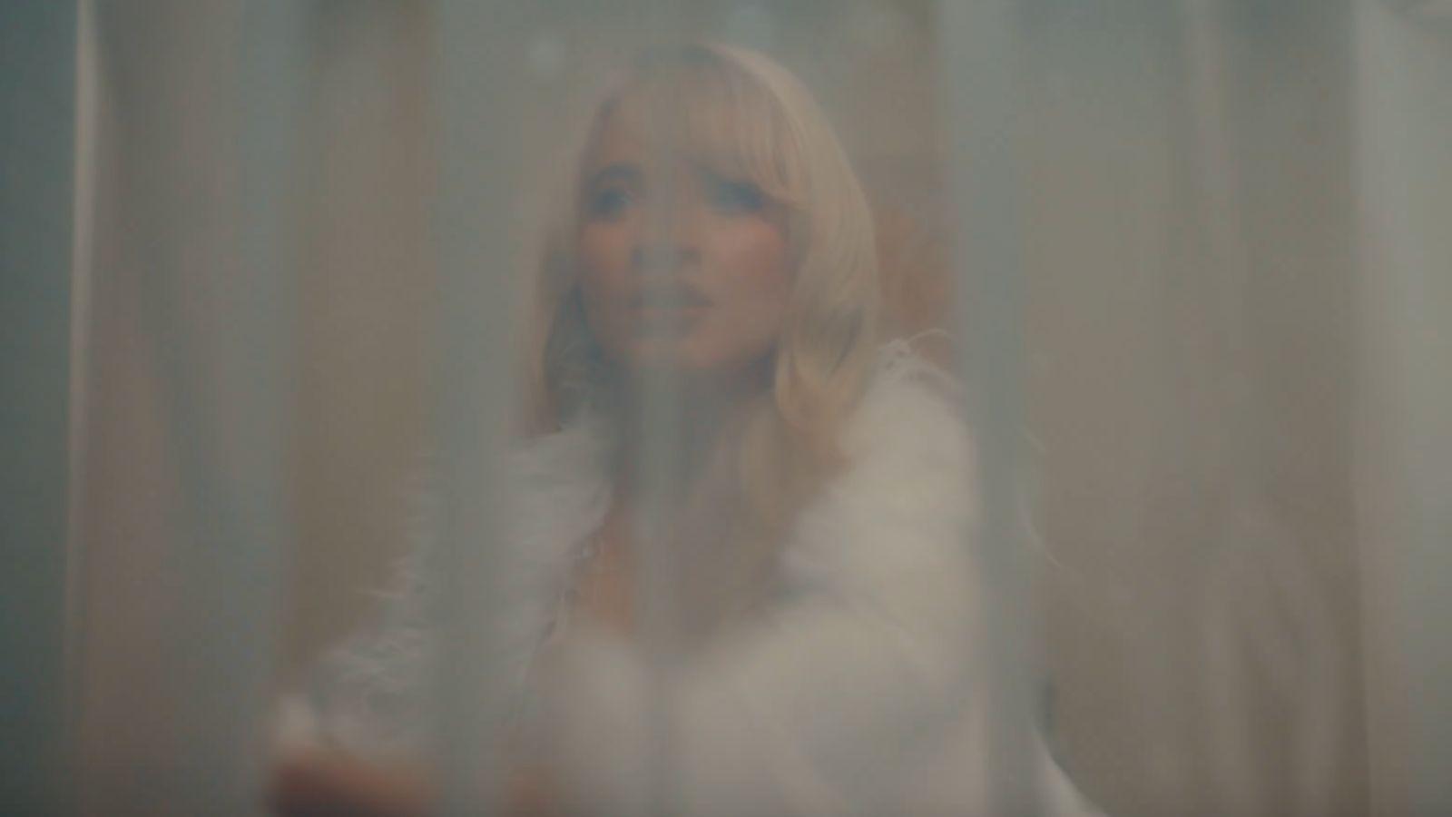 Sabrina Carpenter behind a shower curtain in the music video “Taste”