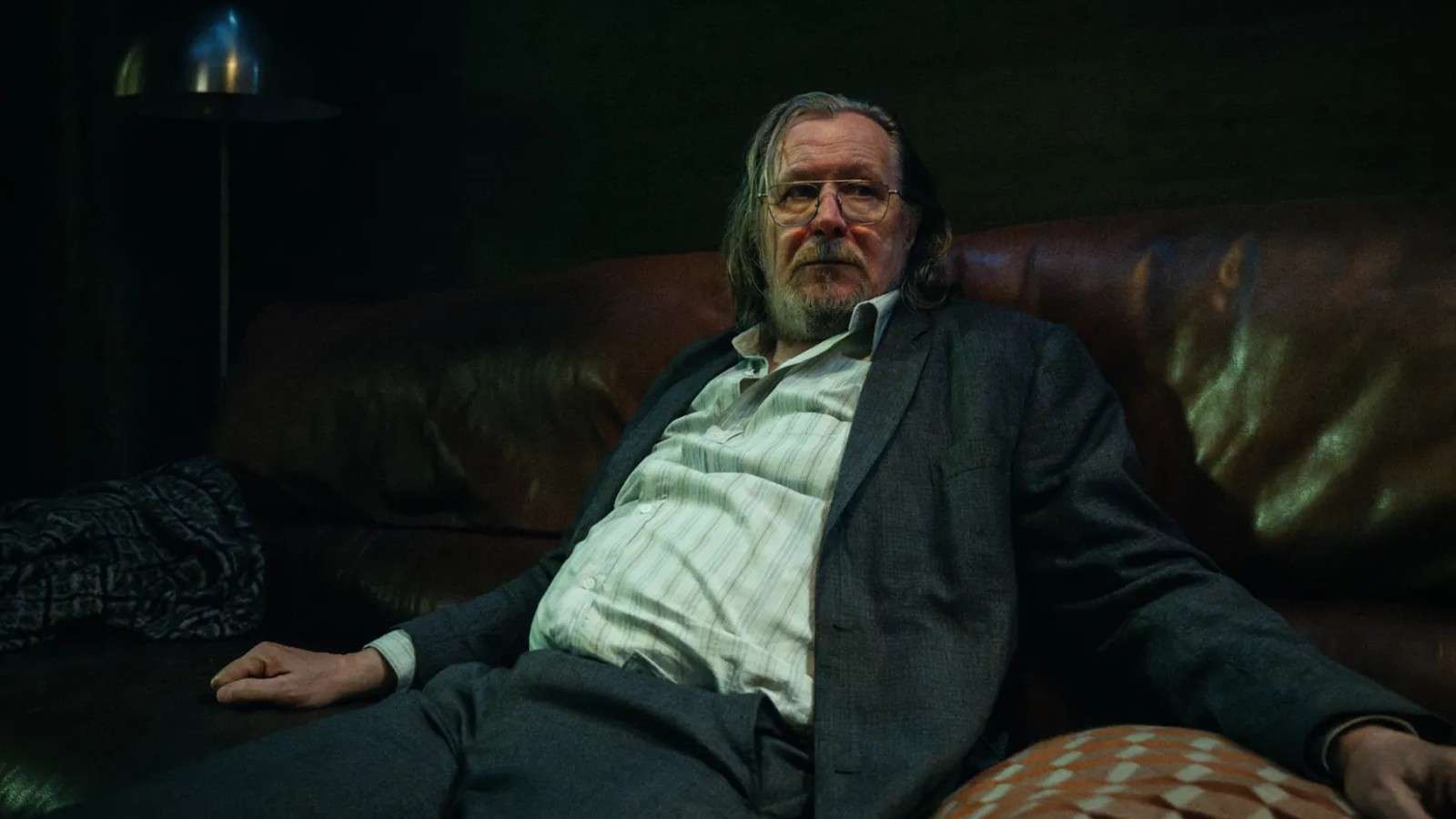 Gary Oldman sitting on a couch in Slow Horses.