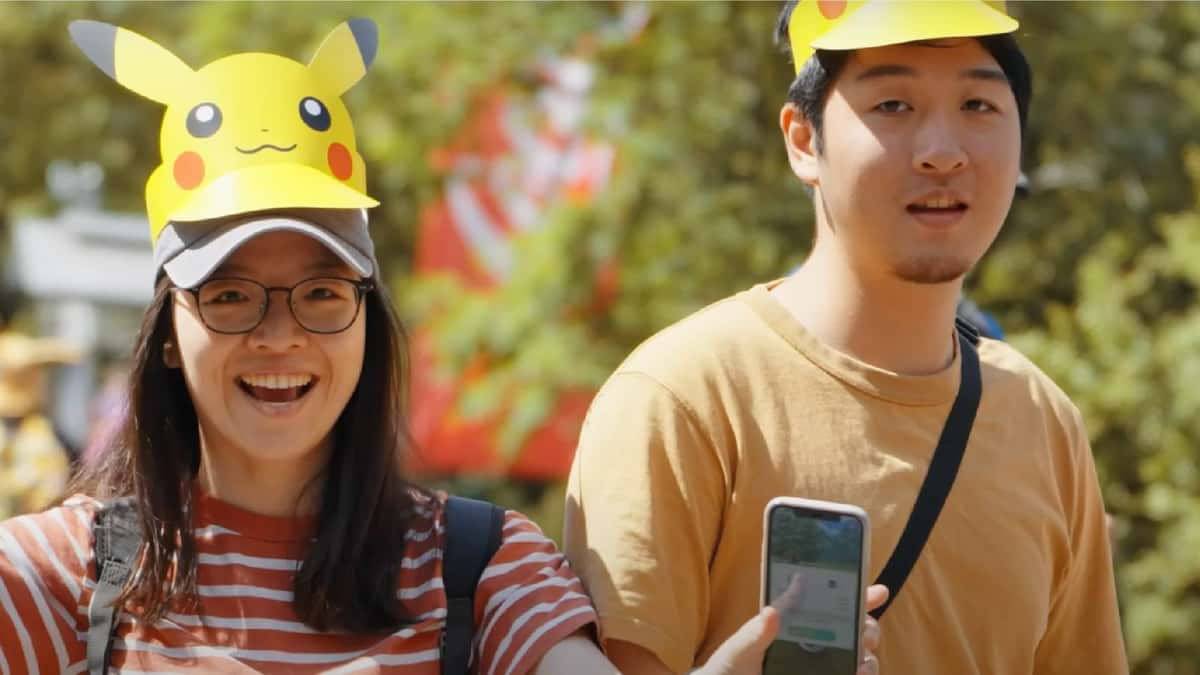 Two people are shown playing Pokemon Go at a physical Pokemon Go event