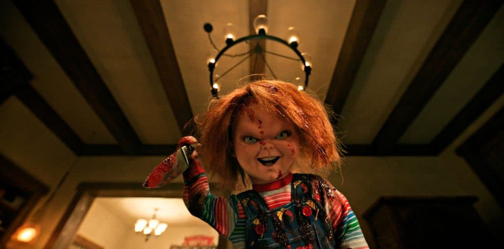 Chucky the doll looking into the camera and holding up a knife