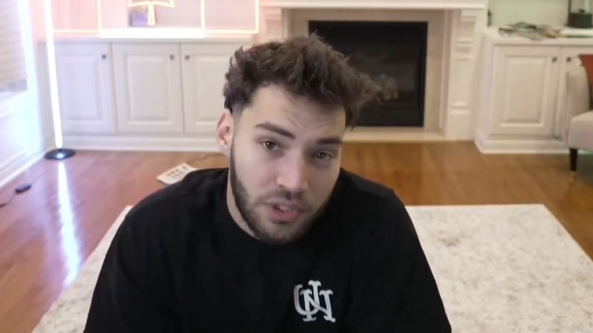 Adin Ross in black t-shirt talking to camera in front of fire