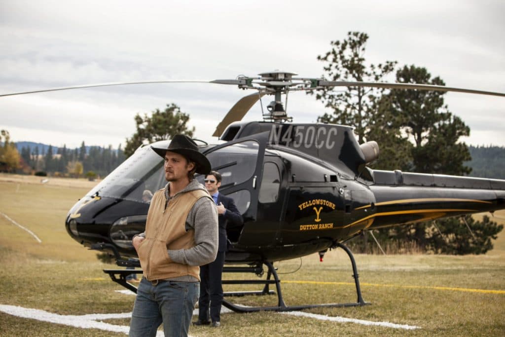 Luke Grimes as Kayce standing in front of the Dutton helicopter in Yellowstone