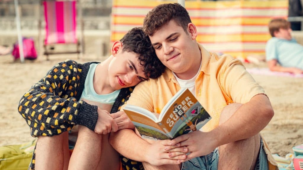 Charlie e Isaac leen un libro en la playa en la temporada 3 de Heartstopper