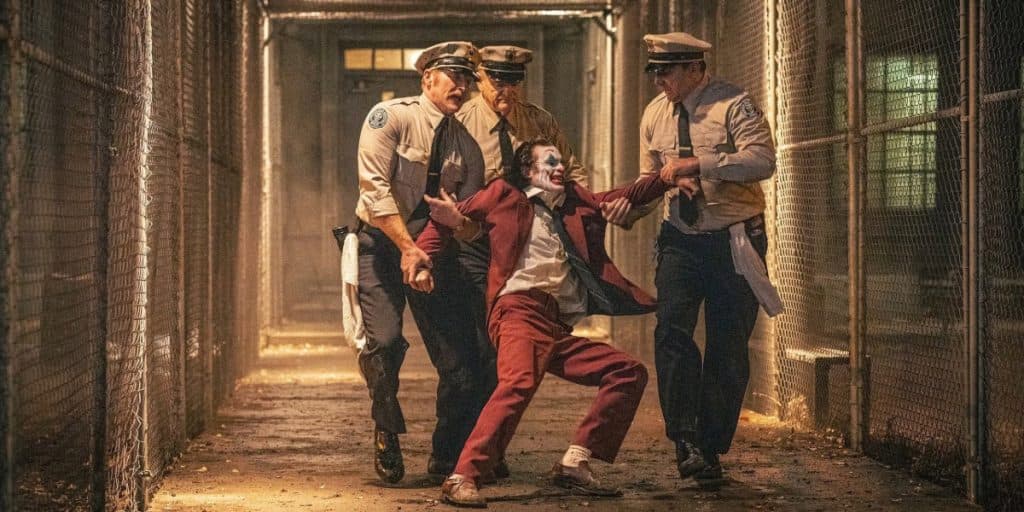 Joaquin Phoenix as Arthur being escorted through Arkham by guards in Joker 2